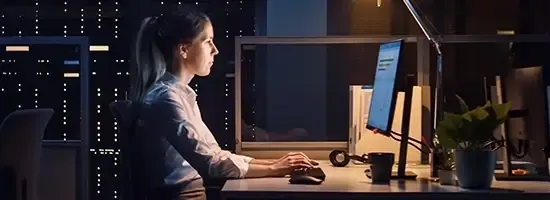 Side view of woman looking at monitor in dark