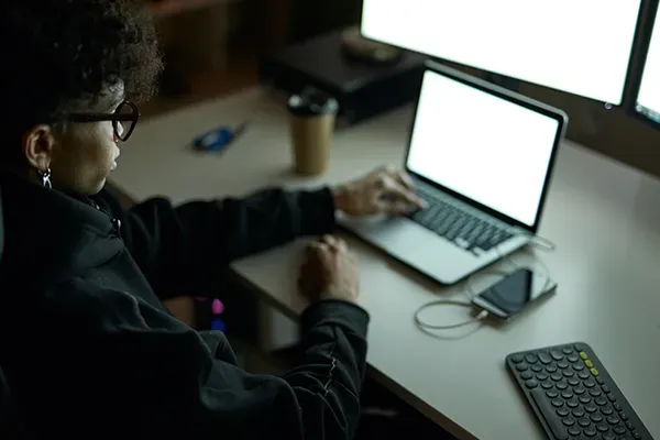 Person with glasses typing on laptop in dark room