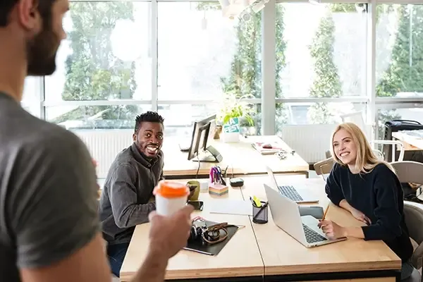 Man and woman smiling while sitting at table with man looking over