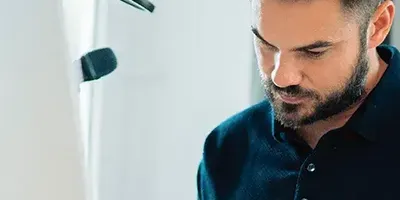 Man with beard looking down at computer screen