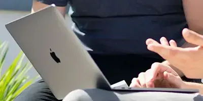 Person with a laptop on their lap while moving hands