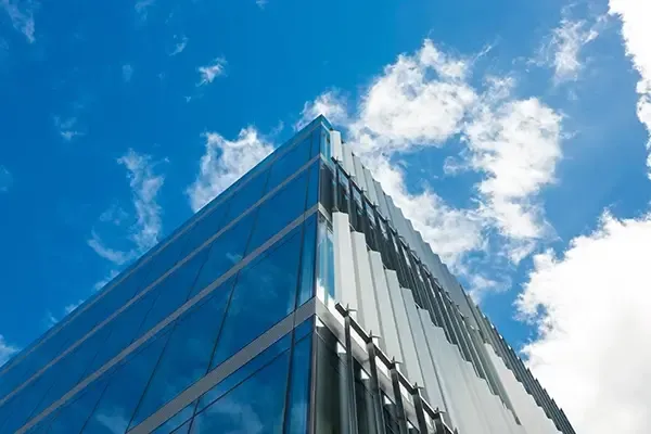 Corner of glass building with clouds in sky