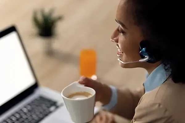 Woman looking at laptop while holding coffee in right hand