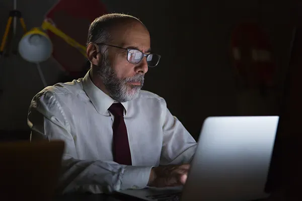 Man with glasses looking down at laptop