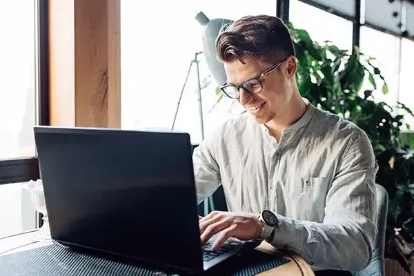Man with glasses typing on laptop