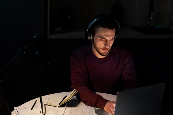 Man with headphones on typing on laptop