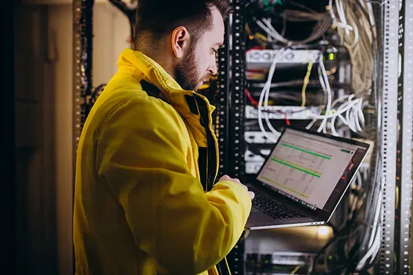 Man in a server room typing on laptop