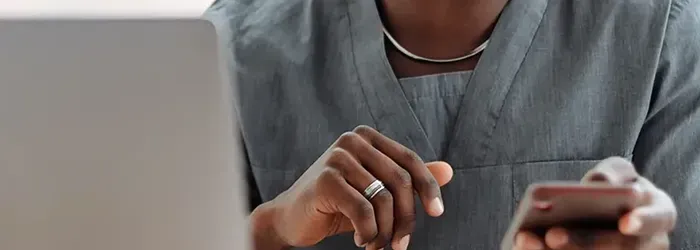 Person using mobile phone with laptop in foreground