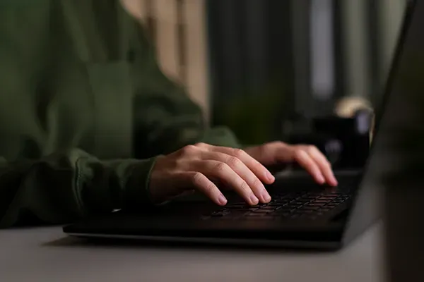 Close-up of person typing on laptop