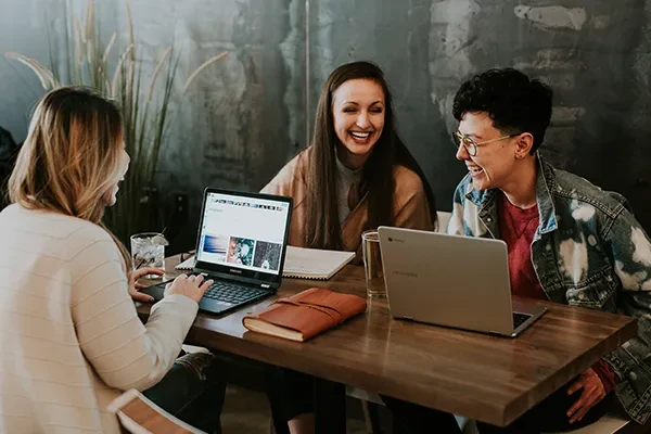 Women in a room with laptops talking to each other