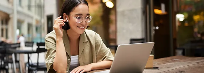 Woman with glasses and AirPods in while using laptop