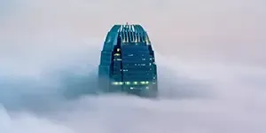 Large glass skyscraper appearing through the clouds