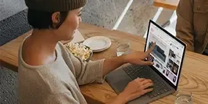 Woman pointing at screen on Microsoft laptop while sitting at table