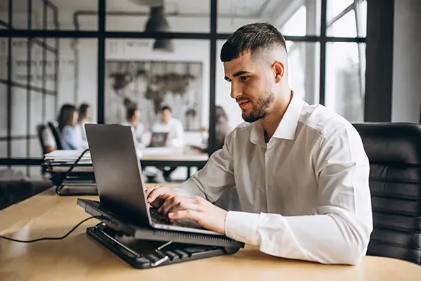 Man with white shirt typing on laptop