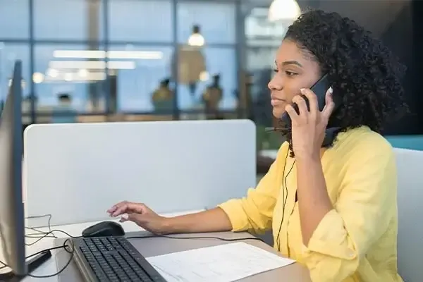 Woman in a yellow dress using VoIP phone systems on a mobile phone