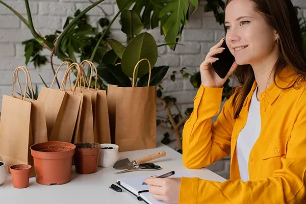 Woman holding phone up to right ear while writing on notepad