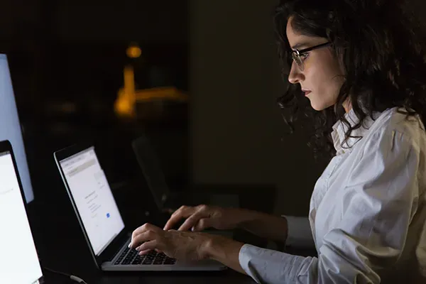 Woman typing on laptop in the dark