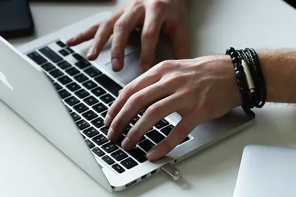 Close up of mans hands typing on laptop