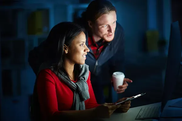 Man and woman smiling while looking at monitor