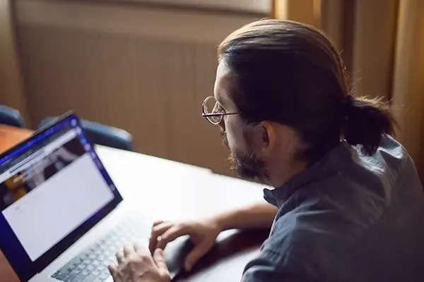 Man with glasses looking down at laptop