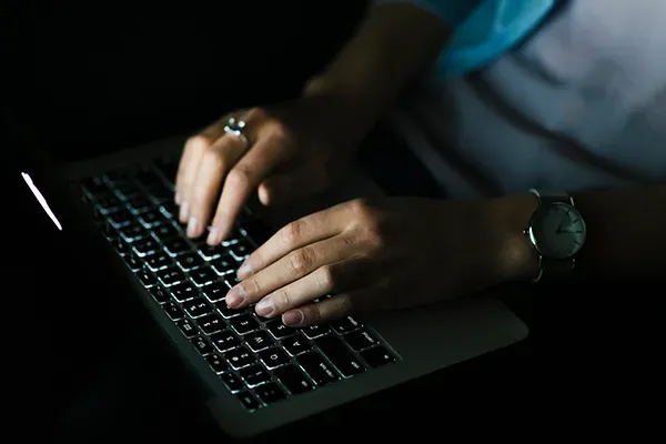 Person typing on laptop in the dark