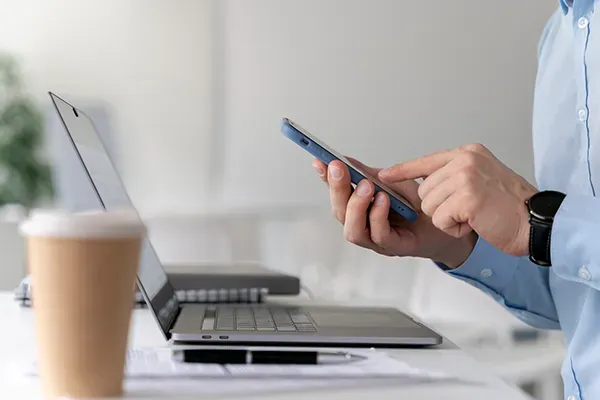 Man using mobile phone with laptop in front