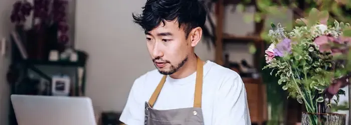 Man in apron working on a laptop