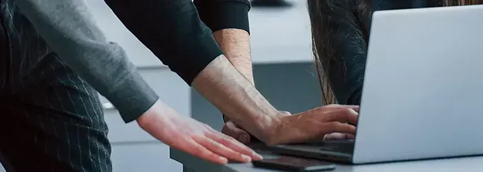 People looking at laptop with hands on desk