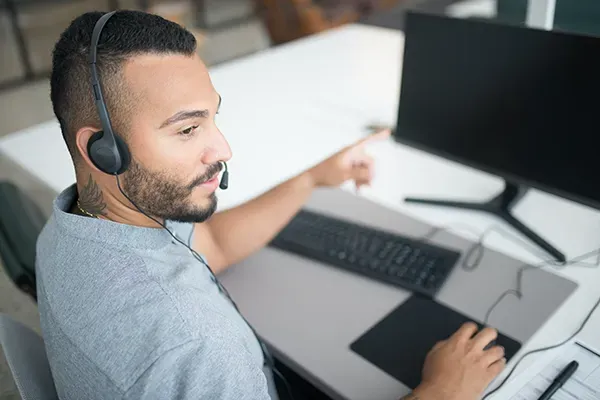 Man pointing at monitor with headset on