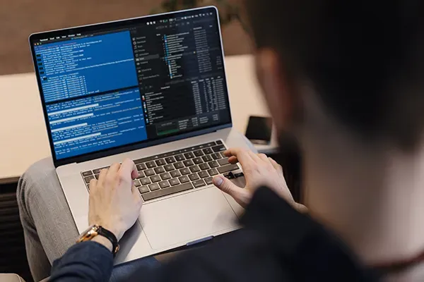 Man typing computer code on laptop