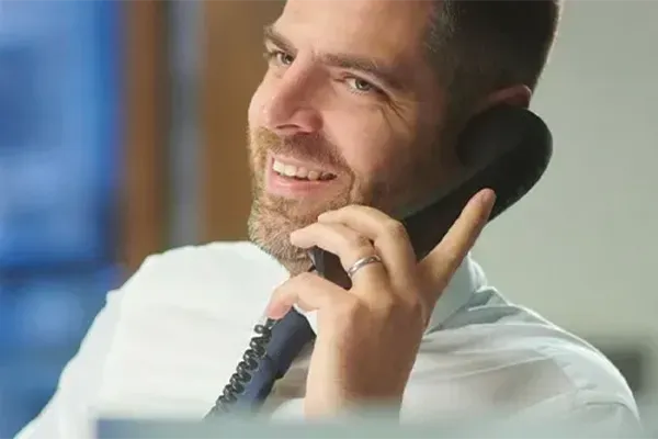 Man smiling while holding telephone up to left ear