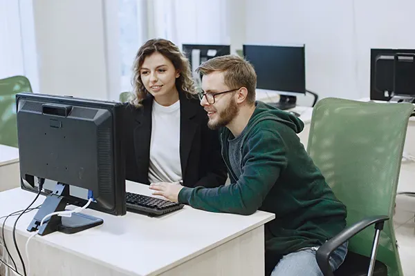 Man with glasses next to woman on computer