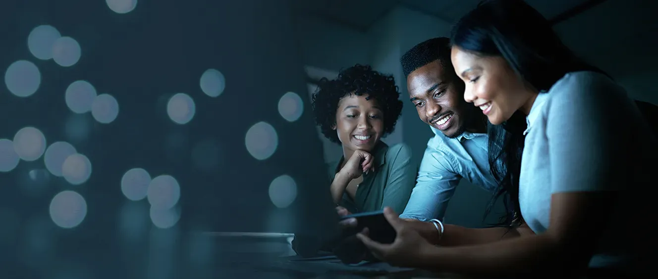 Three people smiling at each other while looking at phone