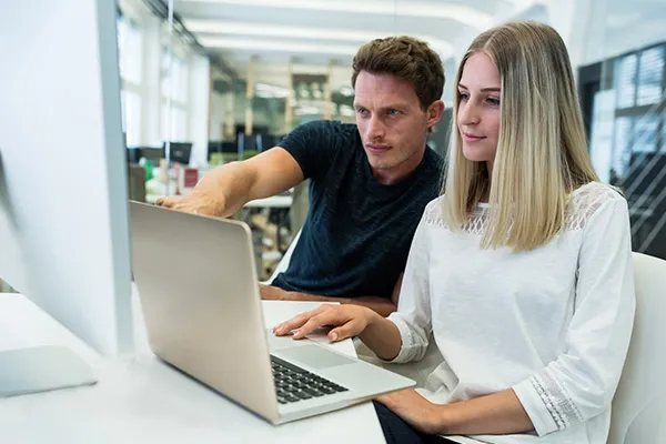Man pointing at laptop while woman looks intriguingly
