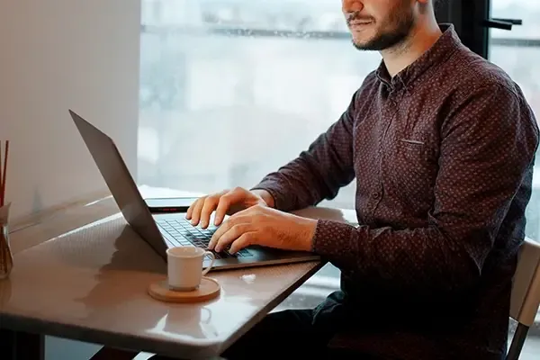 Man typing on laptop while sitting at table