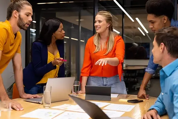 Five people standing around a table while talking