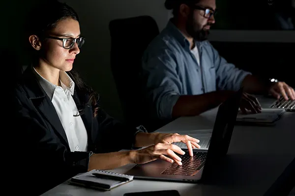 Woman and man with glasses typing on laptops