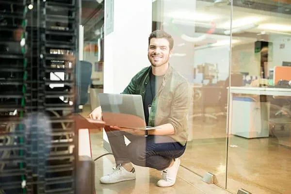 Man smiling at camera with laptop