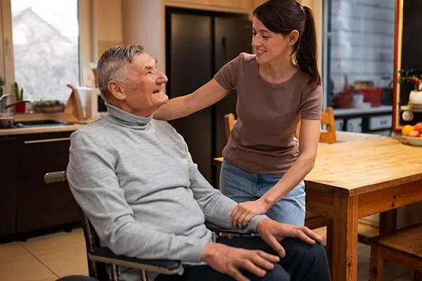 Woman comforting older man in wheelchair