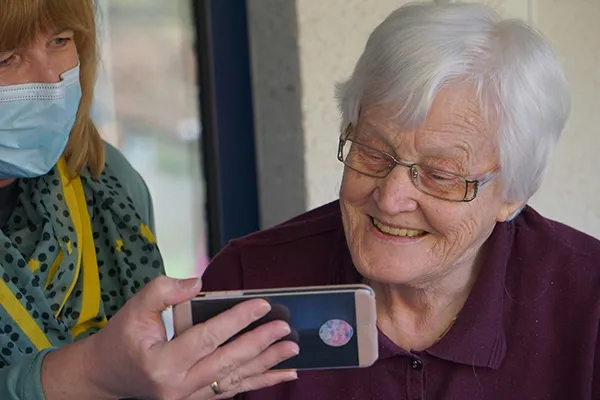 Older woman with glasses looking at woman's mobile phone