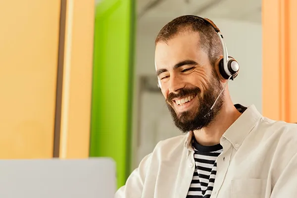 Man smiling with headset on while using laptop