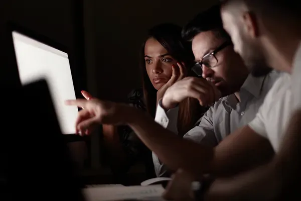 Man pointing at monitor while two other people look