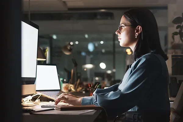 Woman with glasses looking at computer monitor while typing