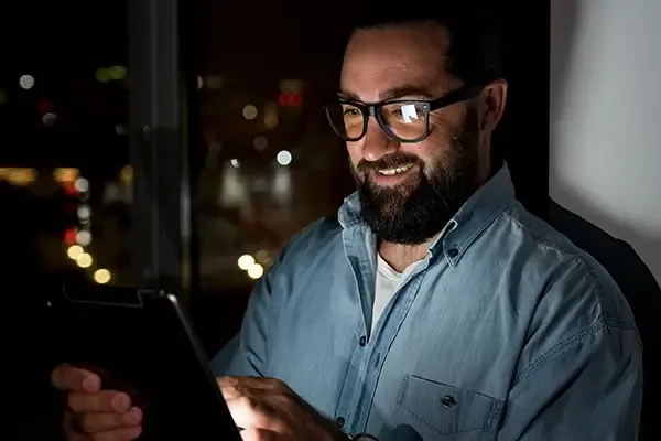 Man with glasses using tablet in dark room