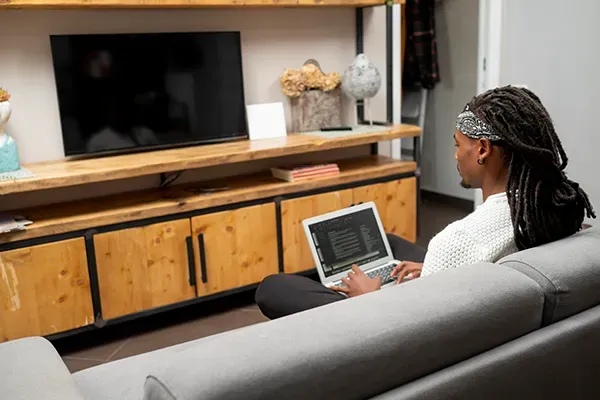 Man sitting on sofa with laptop on lap