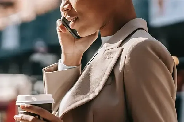 Woman holding a coffee using VoIP calling on her mobile phone
