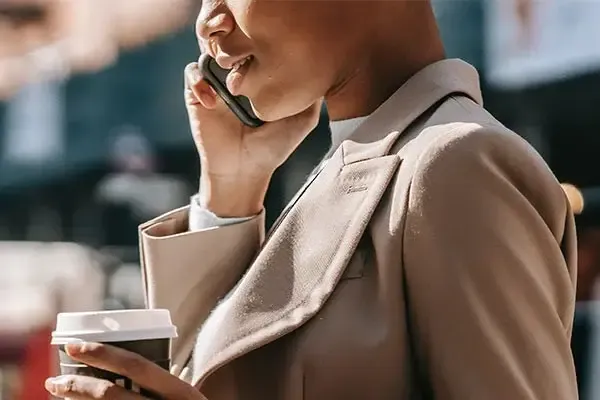 VoIP business phone systems Woman holding a coffee using VoIP calling on her mobile phone