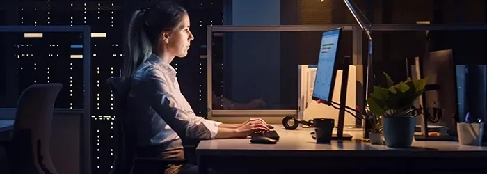 Woman in empty office looking at monitor and typing