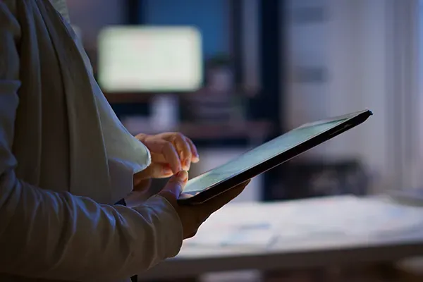 Person holding tablet out in front of them while standing