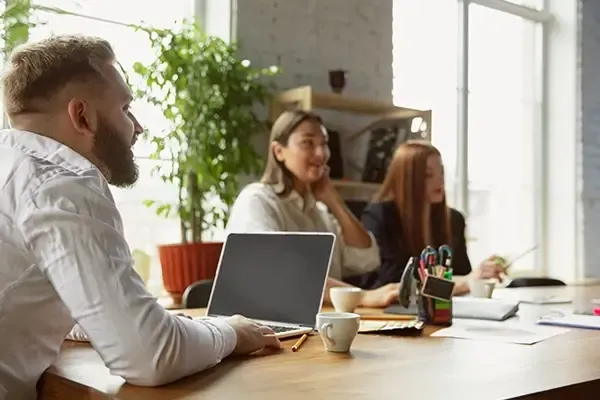 Man sat at table with laptop with two woman